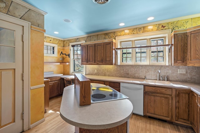 kitchen featuring dishwasher, a center island, plenty of natural light, light wood-type flooring, and ornamental molding