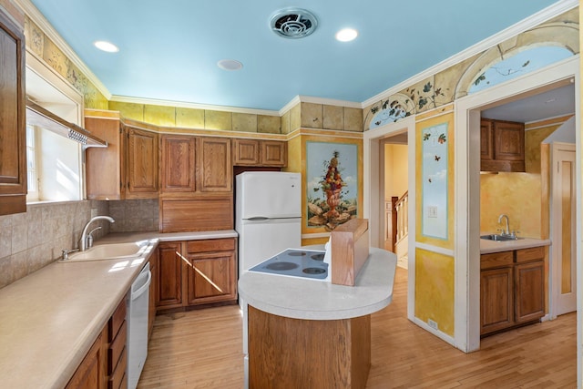 kitchen featuring a sink, decorative backsplash, light countertops, a kitchen island, and crown molding