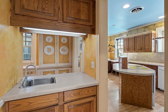 kitchen with a sink, dishwasher, light countertops, and light wood-type flooring