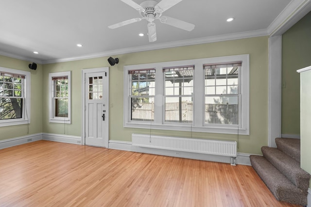 unfurnished living room with radiator heating unit, crown molding, light wood-style floors, stairs, and baseboards