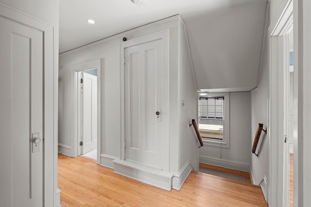 hallway with light wood-style flooring, baseboards, an upstairs landing, and recessed lighting