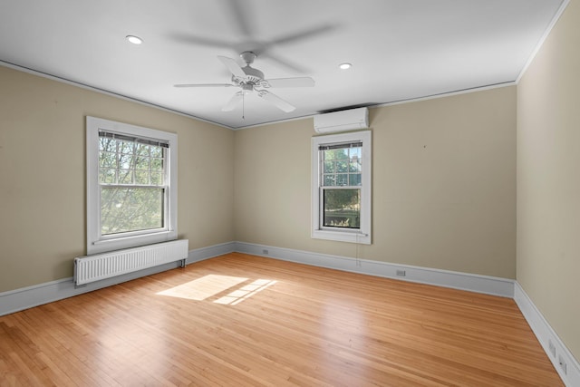 empty room featuring radiator heating unit, a wall mounted AC, plenty of natural light, a ceiling fan, and recessed lighting
