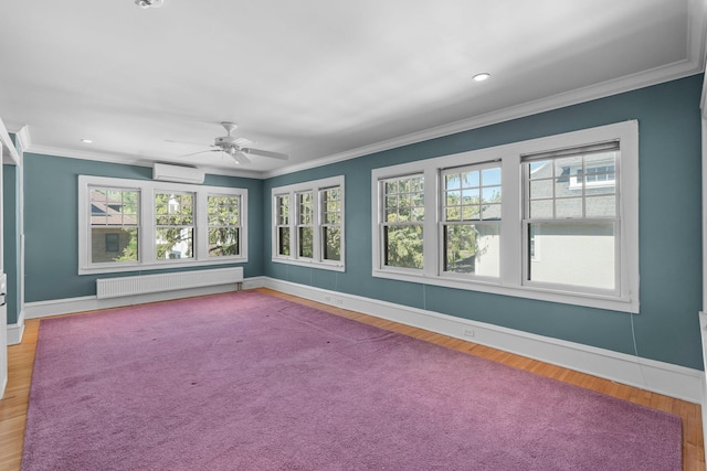 spare room featuring radiator, baseboards, a wall mounted air conditioner, a ceiling fan, and crown molding