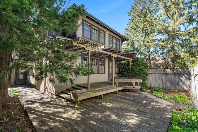 back of property featuring a pergola, a wooden deck, stucco siding, and fence