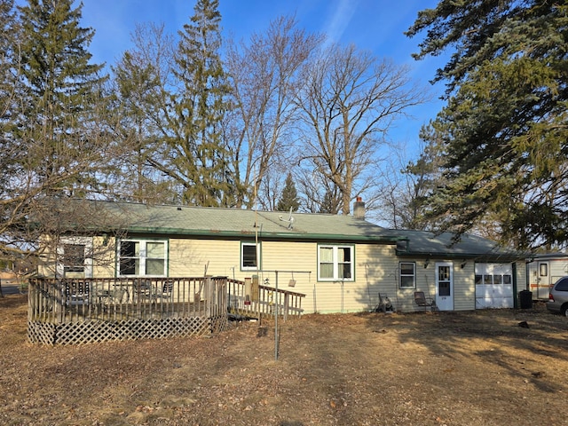 rear view of property with a deck, a garage, and a chimney