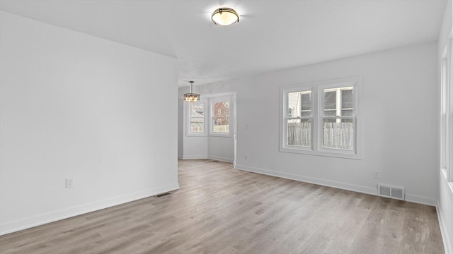 spare room featuring baseboards, visible vents, and light wood finished floors