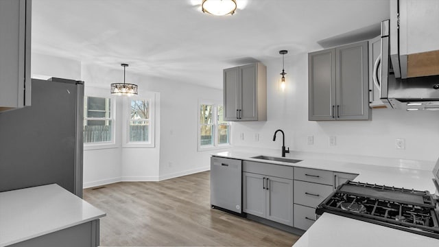 kitchen with a sink, light countertops, gray cabinets, and stainless steel appliances