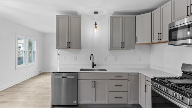 kitchen featuring a sink, stainless steel appliances, gray cabinets, and light wood finished floors