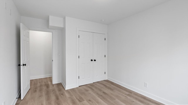 unfurnished bedroom featuring a closet, baseboards, and light wood-style floors