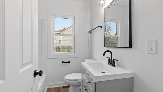 bathroom with baseboards, toilet, a healthy amount of sunlight, and vanity