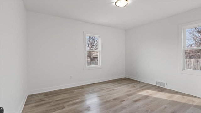 unfurnished room featuring visible vents, light wood-style flooring, and baseboards