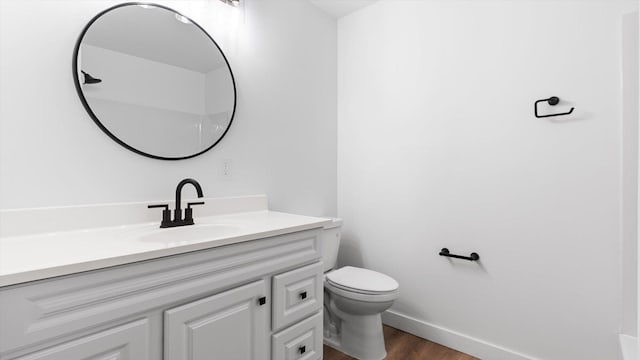 bathroom with vanity, toilet, wood finished floors, and baseboards