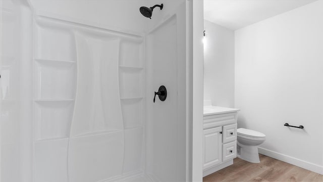 bathroom with baseboards, walk in shower, toilet, wood finished floors, and vanity