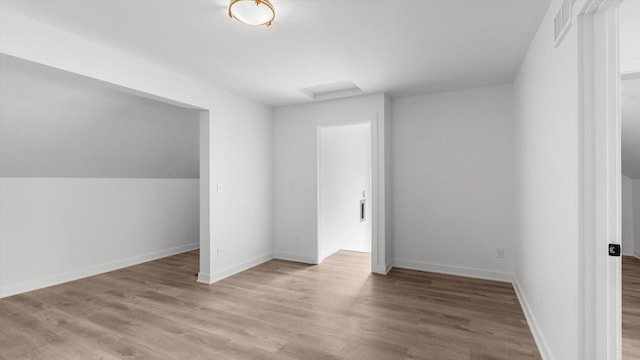 interior space with vaulted ceiling, light wood-style flooring, baseboards, and visible vents