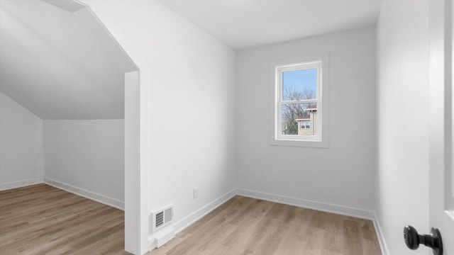 additional living space featuring light wood finished floors, visible vents, and baseboards