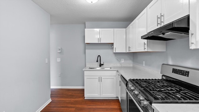 kitchen featuring under cabinet range hood, appliances with stainless steel finishes, dark wood-style floors, white cabinetry, and a sink