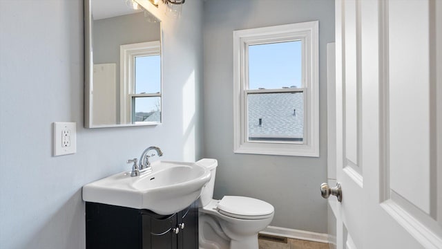 bathroom with visible vents, a healthy amount of sunlight, vanity, and toilet