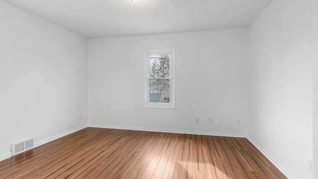 spare room featuring dark wood-type flooring, baseboards, and visible vents