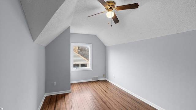 additional living space featuring visible vents, ceiling fan, baseboards, wood finished floors, and a textured ceiling