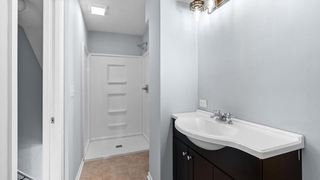 full bathroom featuring a stall shower, vanity, and tile patterned flooring