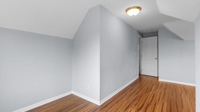 additional living space with vaulted ceiling, wood finished floors, and baseboards