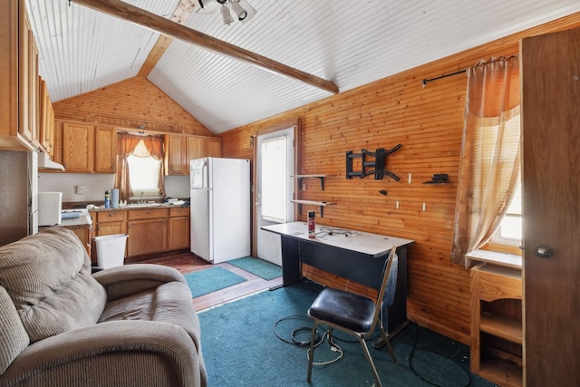 living room with lofted ceiling with beams, wooden walls, and light colored carpet