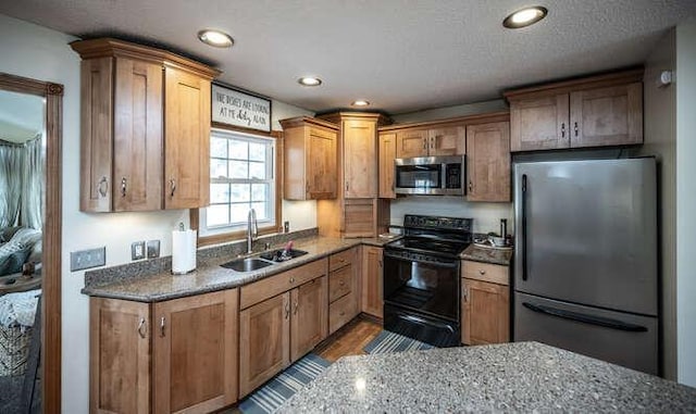 kitchen with dark stone counters, recessed lighting, appliances with stainless steel finishes, and a sink