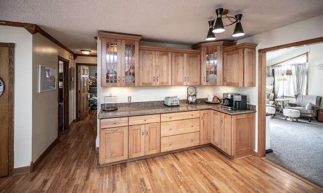 kitchen featuring glass insert cabinets, baseboards, a textured ceiling, and light wood finished floors