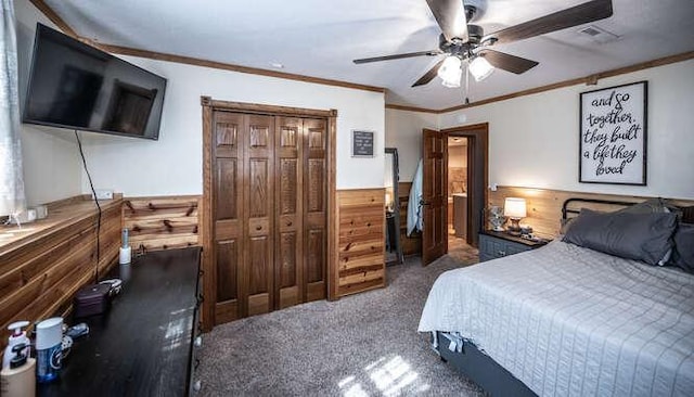 carpeted bedroom featuring a wainscoted wall, visible vents, wooden walls, crown molding, and ceiling fan