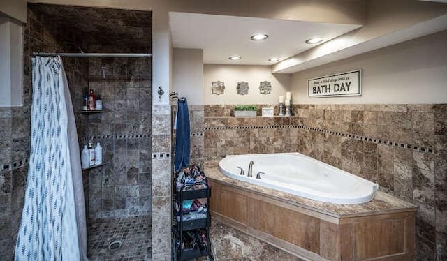 full bath with a bath, tiled shower, and tile walls