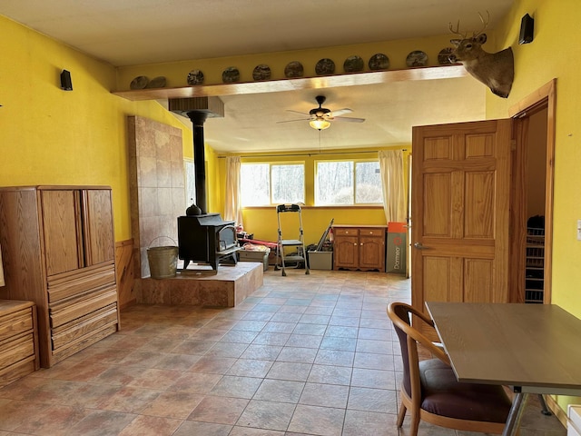 interior space with a wood stove and a ceiling fan