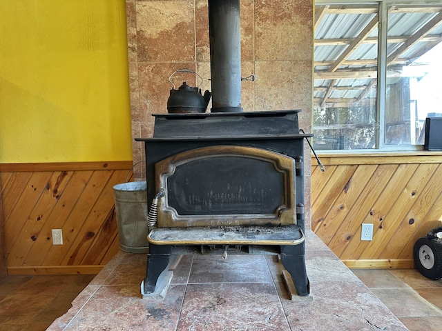 details featuring a wainscoted wall, wood walls, and a wood stove