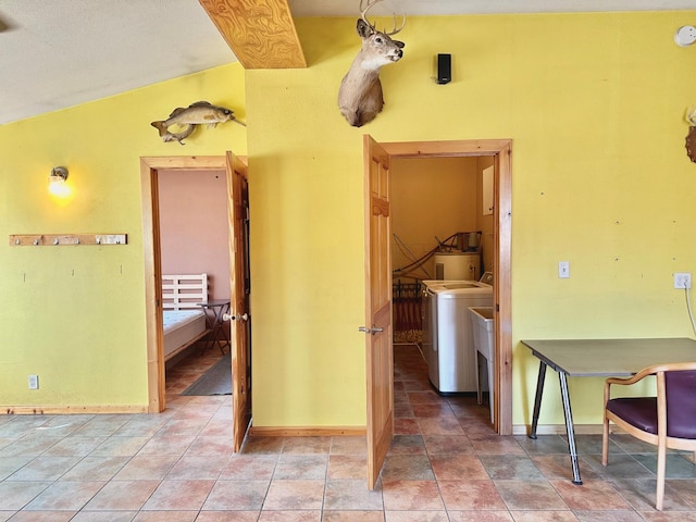 interior space featuring light tile patterned floors, baseboards, separate washer and dryer, and vaulted ceiling