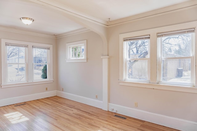 unfurnished room featuring light wood-style floors, plenty of natural light, baseboards, and visible vents