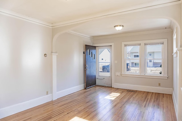 entrance foyer featuring baseboards, arched walkways, wood finished floors, and crown molding