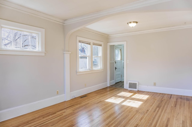 empty room featuring visible vents, baseboards, light wood-style floors, and ornamental molding