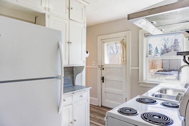 kitchen featuring light countertops, light wood-style floors, white appliances, white cabinetry, and a sink