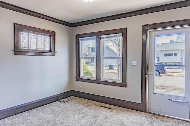 unfurnished room featuring baseboards, visible vents, carpet floors, and ornamental molding