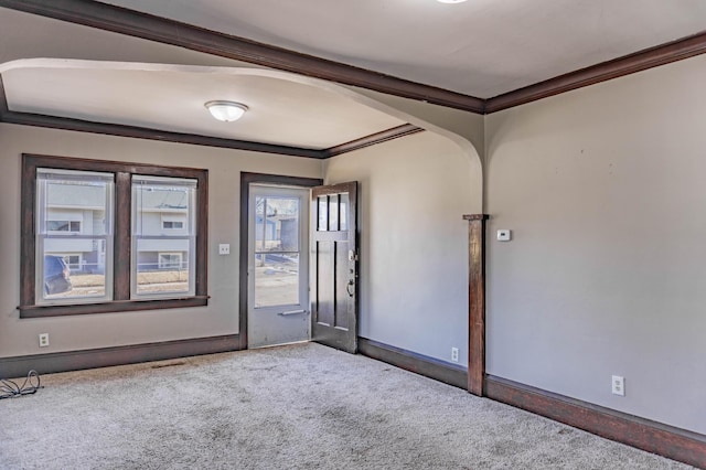 empty room featuring carpet, arched walkways, and ornamental molding