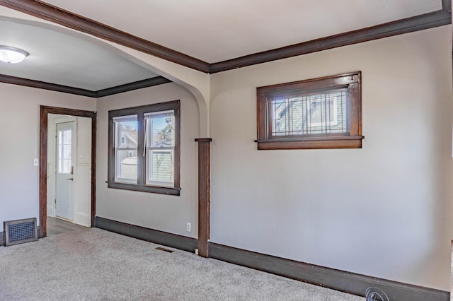 foyer entrance featuring visible vents, carpet flooring, and crown molding