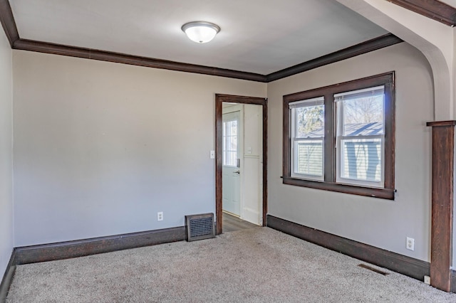 empty room featuring visible vents, carpet floors, and ornamental molding