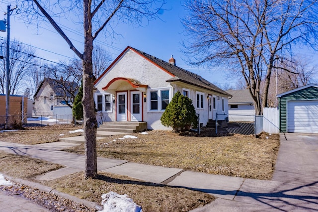 view of front of home featuring a detached garage, an outdoor structure, a chimney, and fence