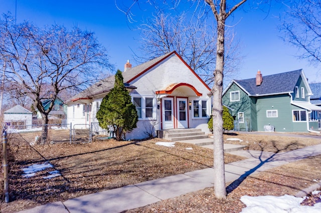 bungalow-style house featuring a chimney and fence