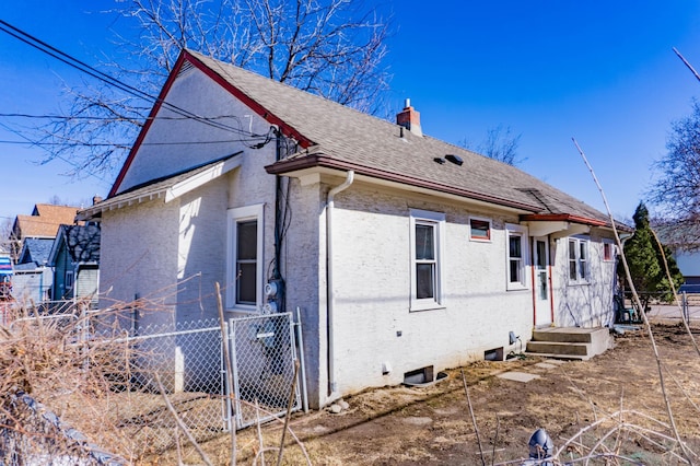 exterior space featuring a shingled roof, stucco siding, fence, and a chimney