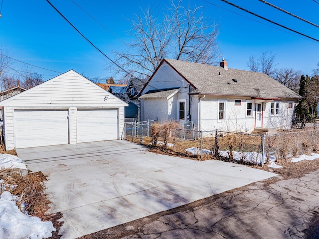 view of front facade with a shingled roof, a chimney, an outdoor structure, a garage, and a fenced front yard