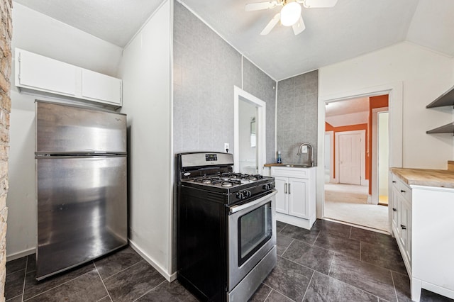 kitchen featuring open shelves, a sink, stainless steel appliances, ceiling fan, and vaulted ceiling