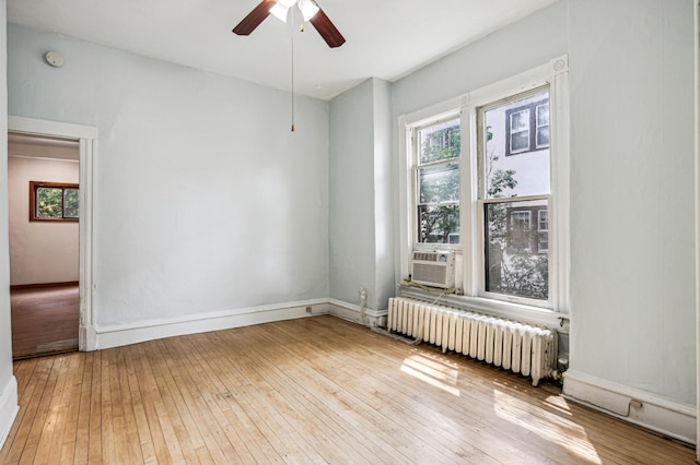 unfurnished room featuring baseboards, radiator heating unit, cooling unit, a ceiling fan, and wood-type flooring