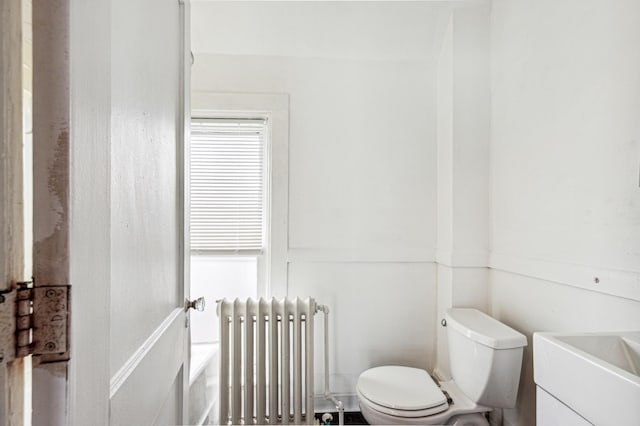 bathroom with a wealth of natural light, radiator, toilet, and a sink