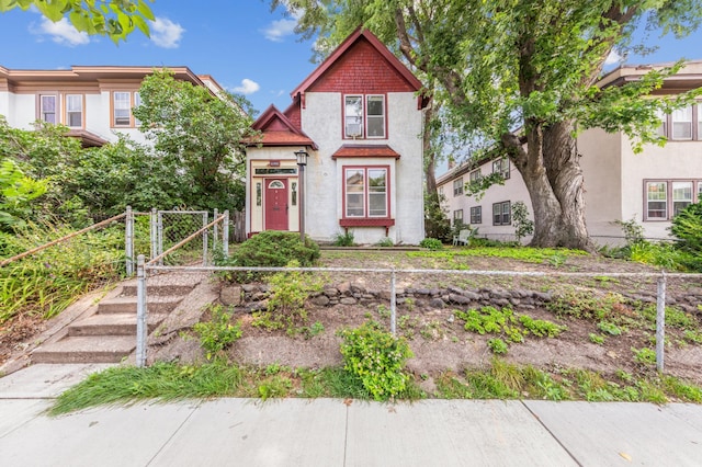 view of front of home with stucco siding, fence, and a gate