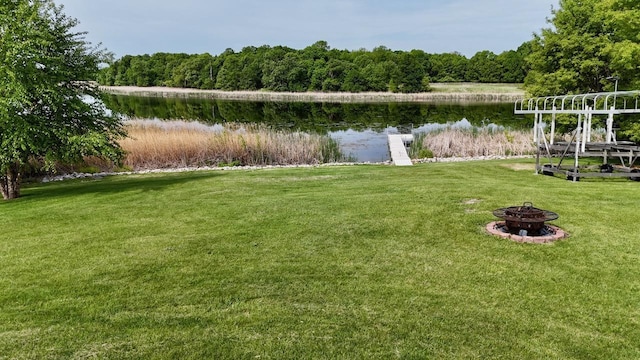 32406 Starland Shore Dr, Dent, MN 56528 - view of green lawn with an outdoor fire pit, a water view, and a wooded view